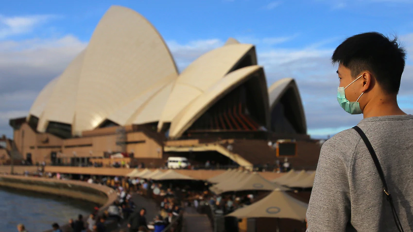People wear face masks at the Sydney Opera House in Sydney, Monday, March 9, 2020. Three people have now died from coronavirus in Australia, while about 75 have tested positive. (AAP Image/Steven Saphore) NO ARCHIVING